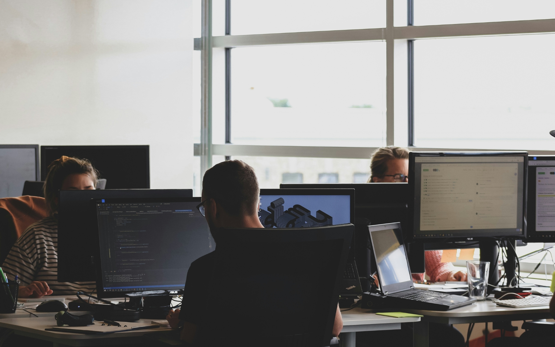 Postazioni di lavoro in un ufficio operativo con schermi e operatori al lavoro
