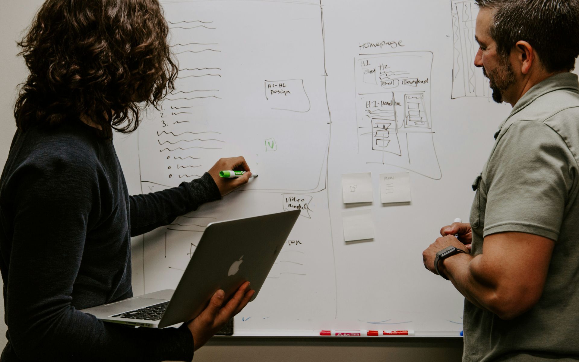 Team collaborating around a whiteboard and laptop to optimize workflows and decision throughput using artificial intelligence