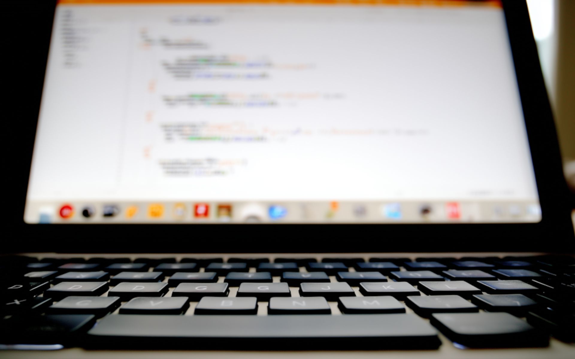 Laptop aperto con codice sfocato sullo schermo e tastiera in primo piano