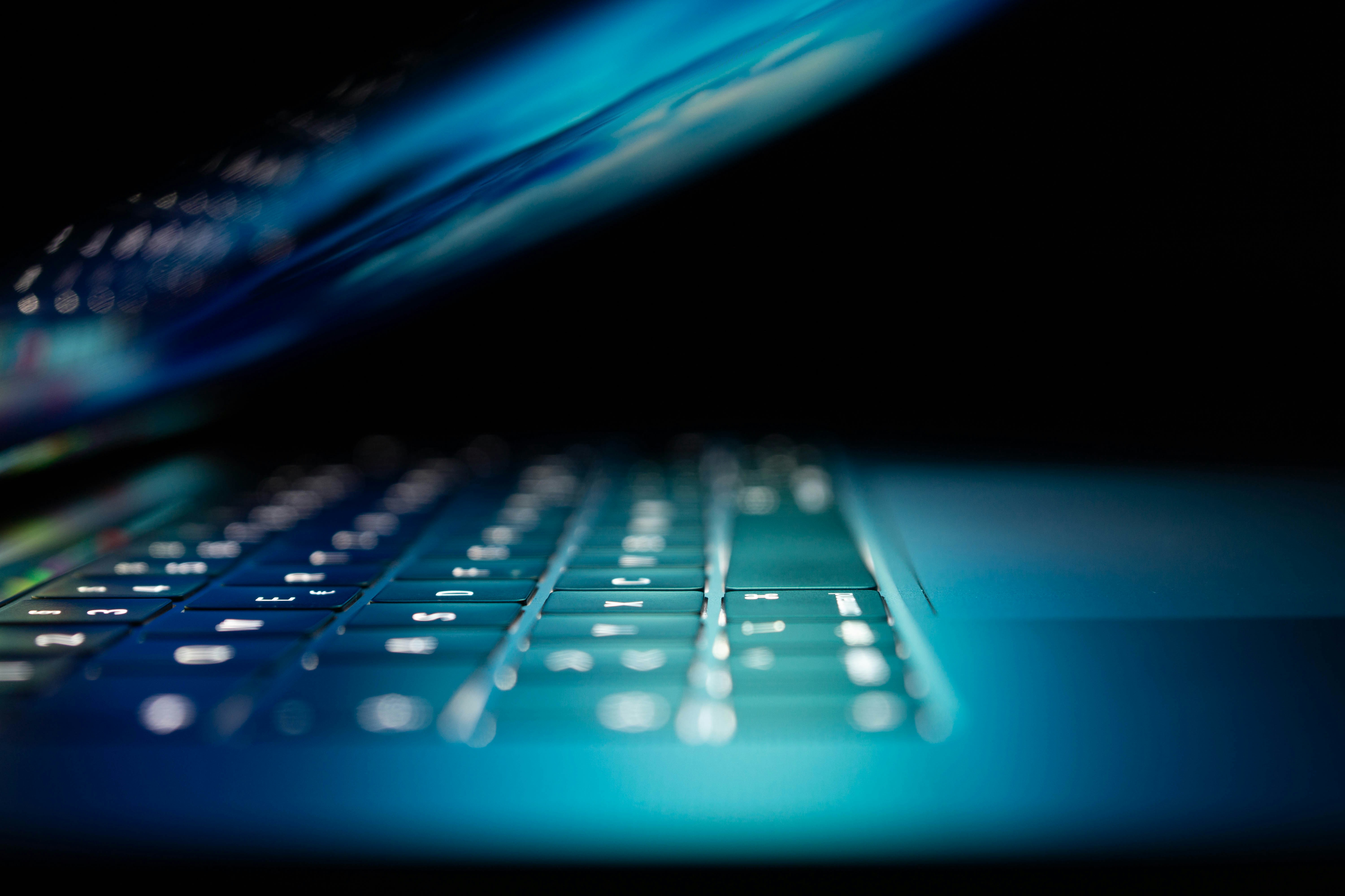 Tastiera di laptop illuminata in blu che rappresenta l’uso di intelligenza artificiale generativa e i rischi per privacy e dati personali nei modelli AI opt‑out.