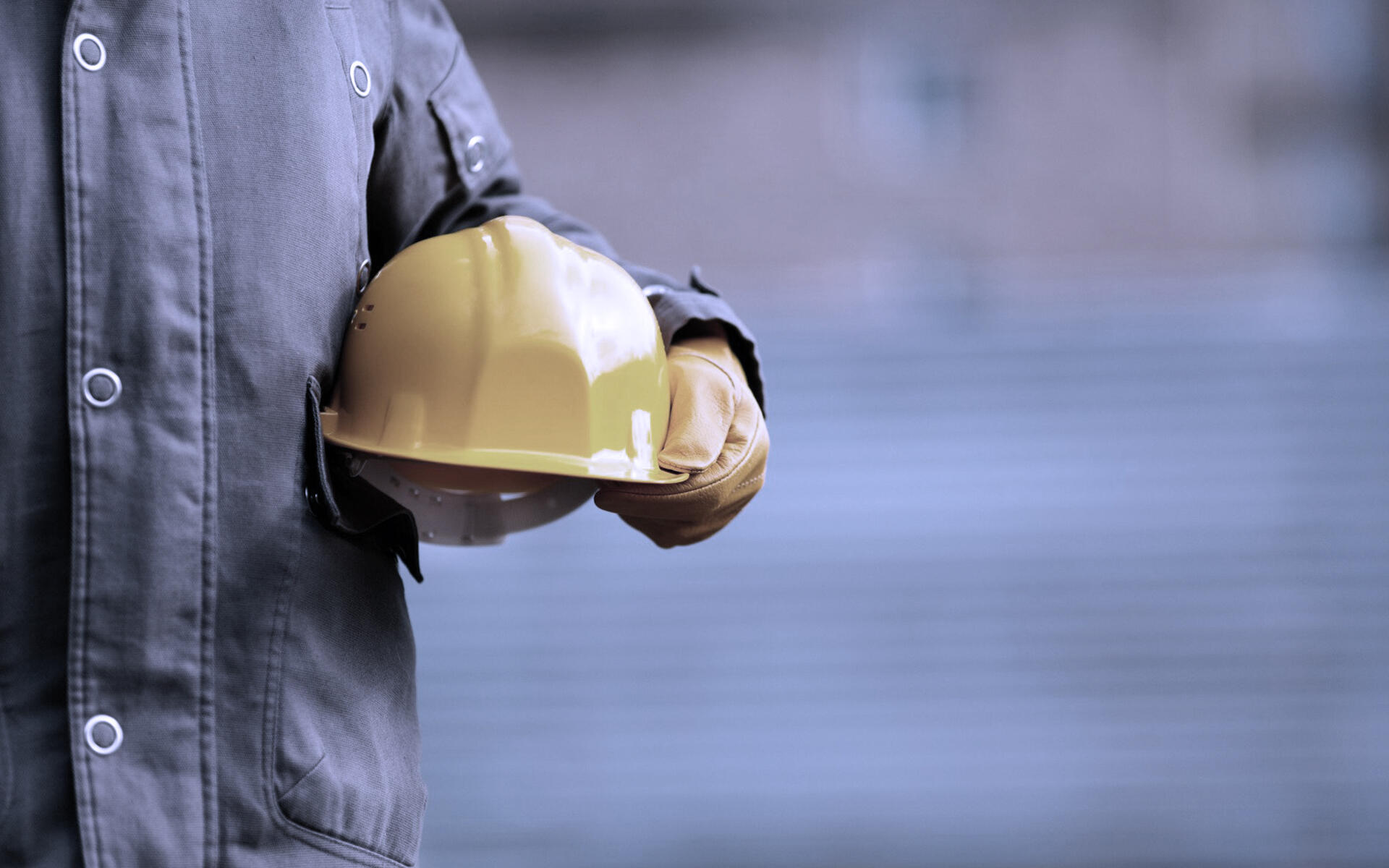 A worker on a construction site holding a protective helmet